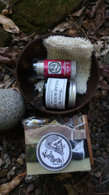 Skincare products including a jar of sugar scrub, soap, and deodorant  on a natural background