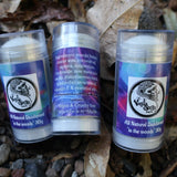 Three in the woods violet deodorant sticks with vanilla gorilla labels on a natural background of leaves and stones