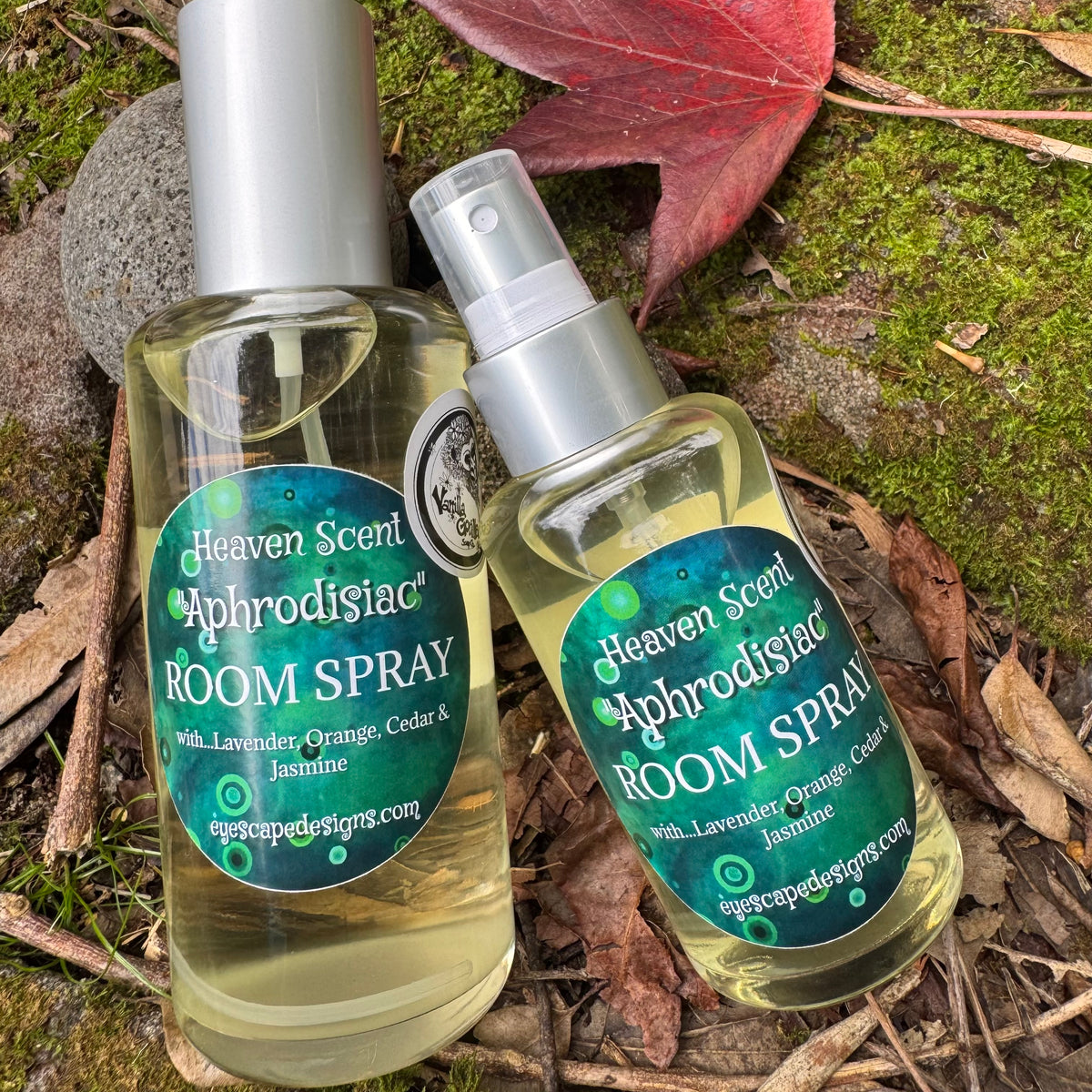 Two bottles of Heaven Scent Aphrodisiac Room Spray on a natural background with leaves and moss.