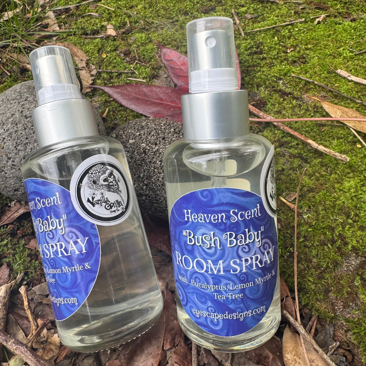 Two bottles of 'Heaven Scent Bush Baby' room spray on a natural background with leaves and moss.