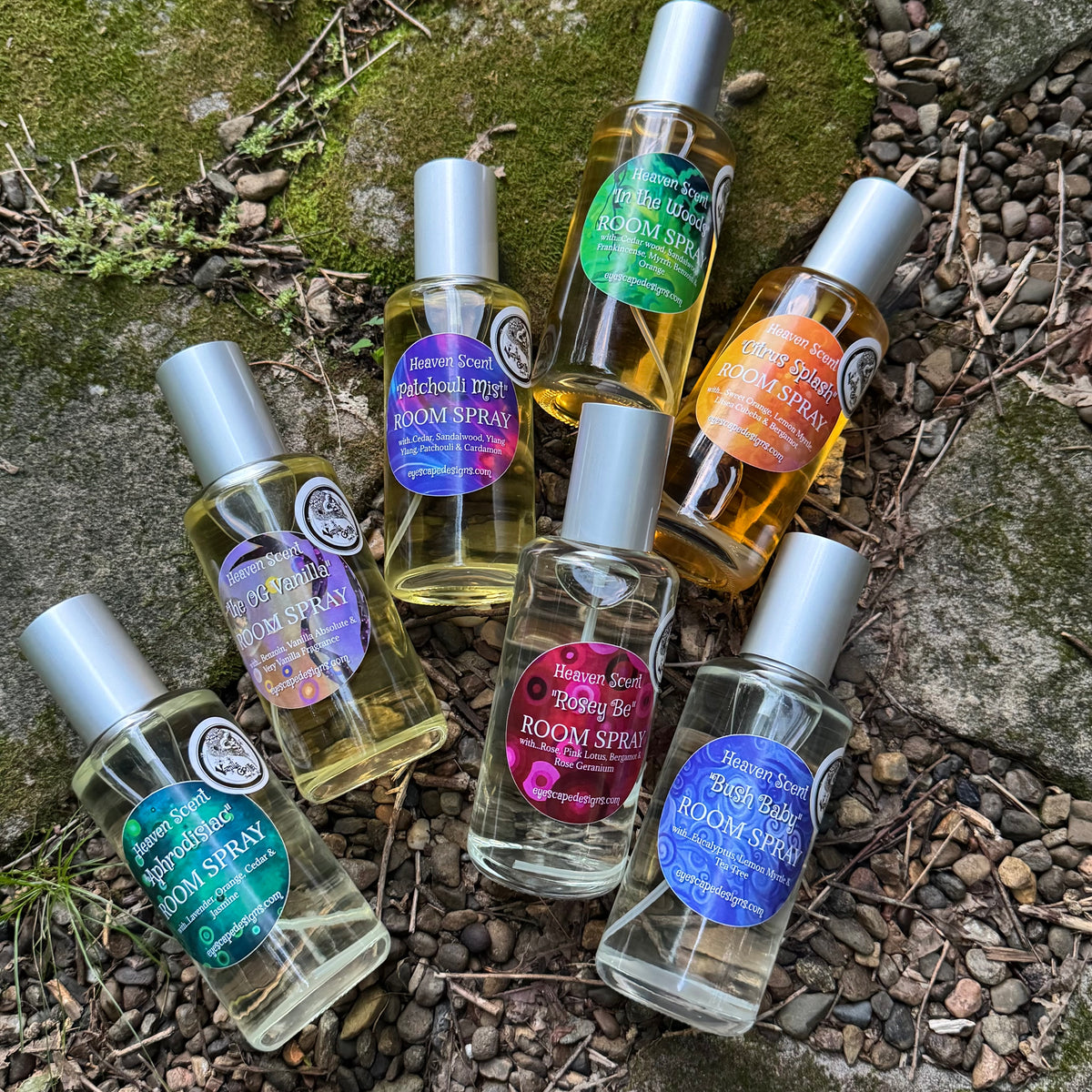 Collection of room spray bottles on a stone surface with greenery.