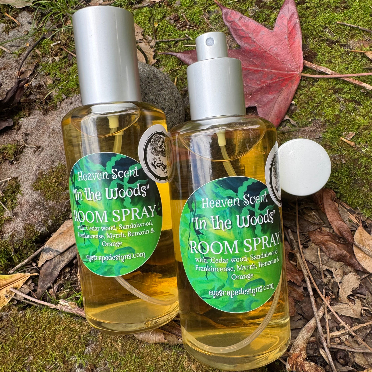 Two bottles of 'Heaven Scent In the Woods' room spray on a natural background with leaves and moss.