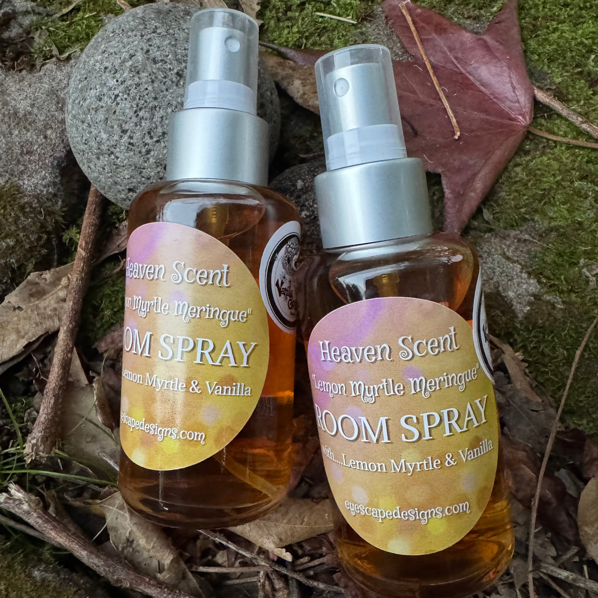 Two bottles of Heaven Scent lemon Myrtle meringue room spray in glad bottles on a natural background with leaves and stones.