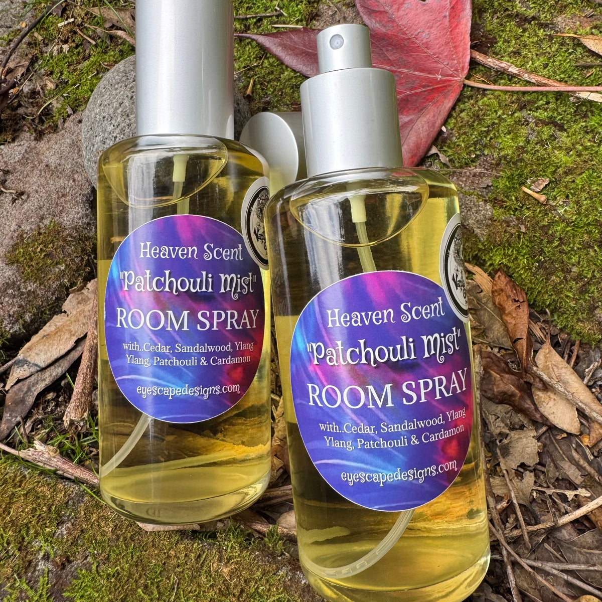 Two bottles of Heaven Scent Patchouli Mist Room Spray on a natural background with leaves and moss.