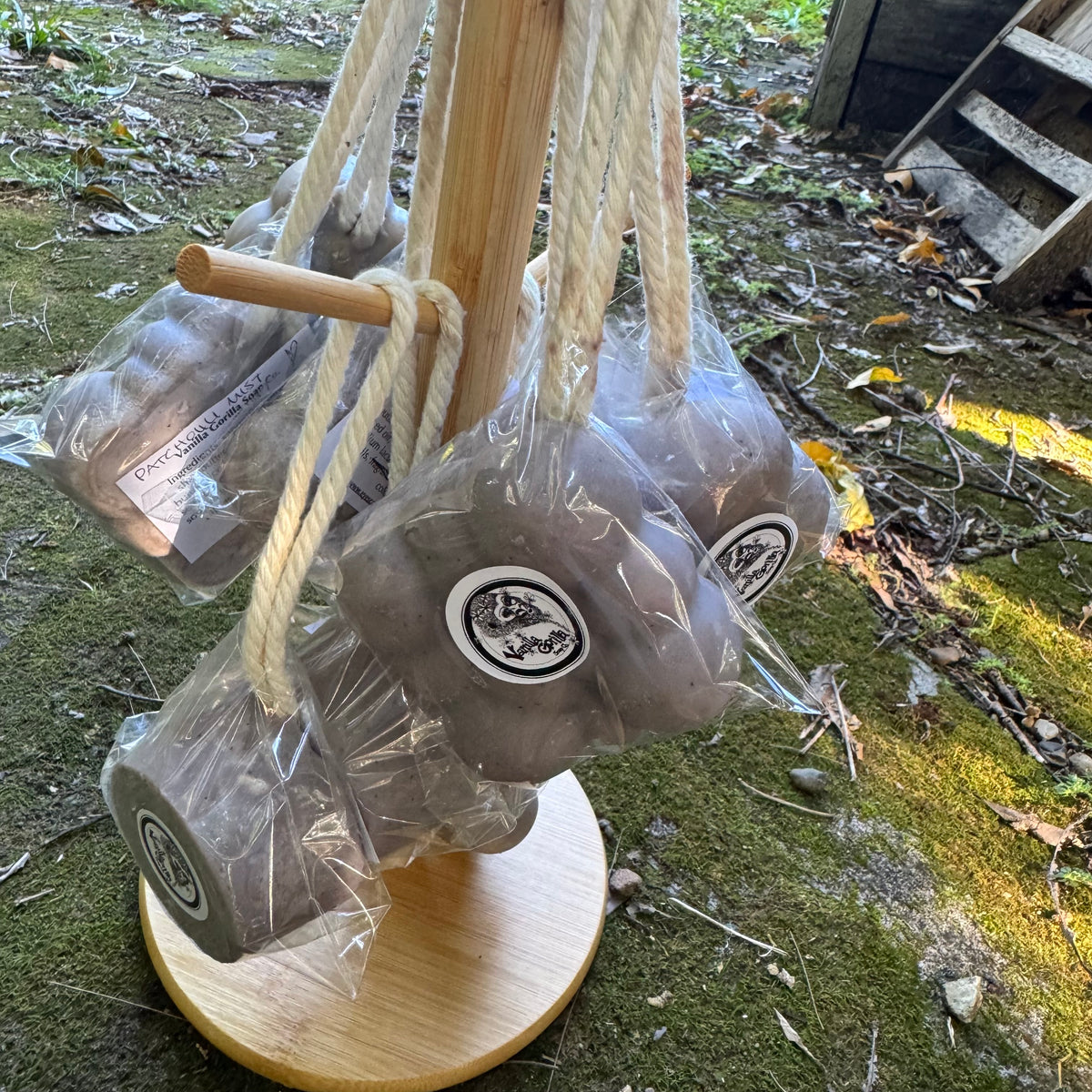 Purple soap on a ropes on a wooden stand with cello wrap, outdoors.