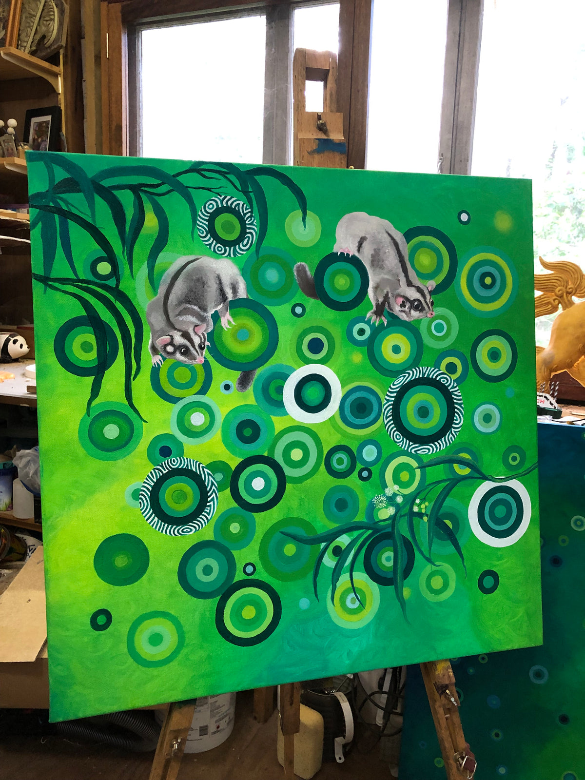 Oil painting on easel of sugar gliders in a sea o green circles