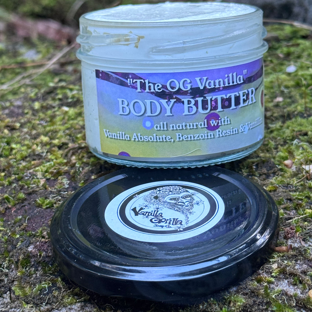 Vanilla body butter natural on a mossy rock with lid off