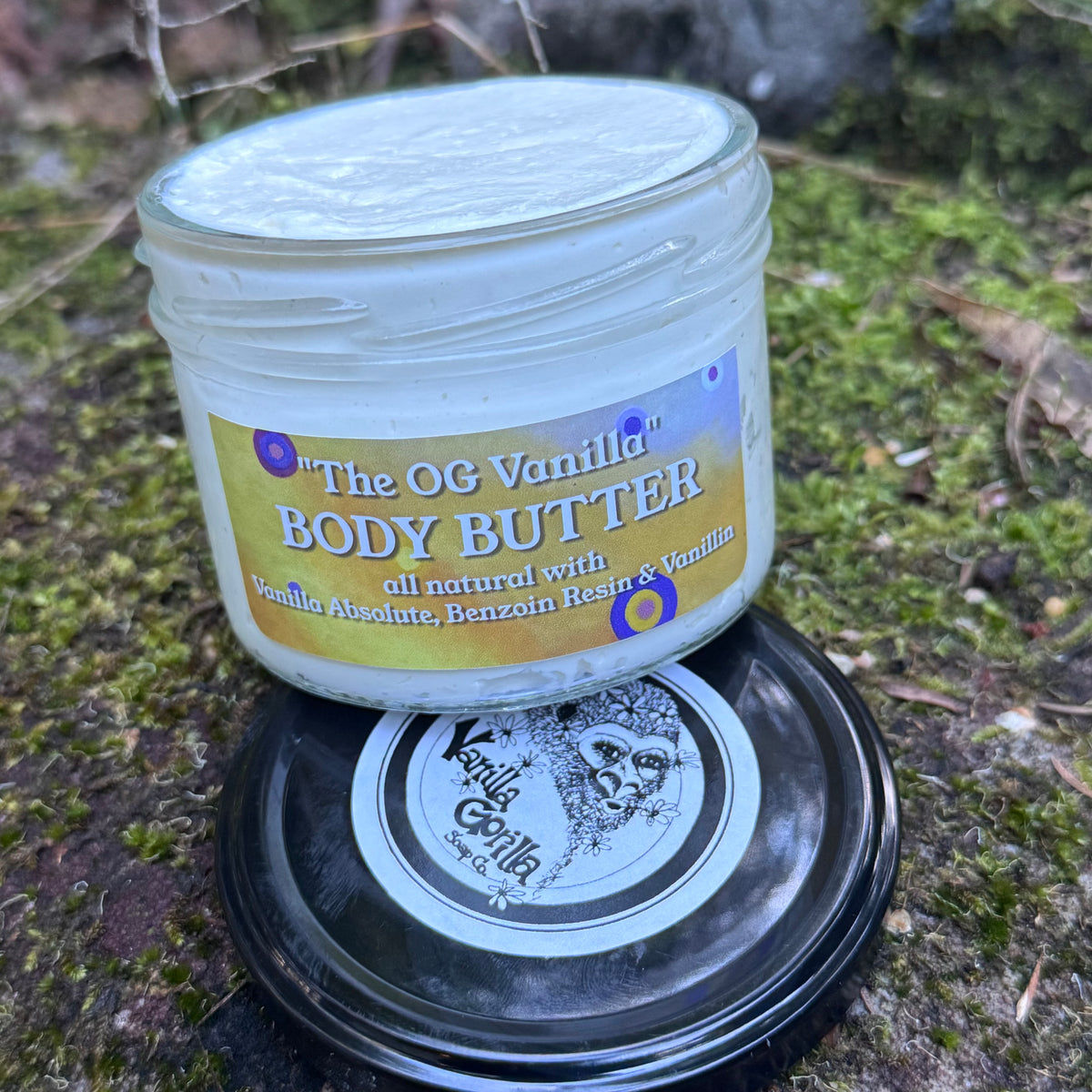 Vanilla natural body butter on a mossy rock background open showing white butter contents