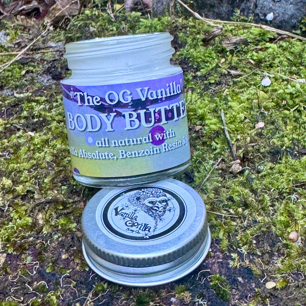 Small jar of vanilla gorilla body butter on a green mossy rock background 