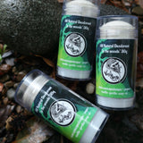 Three all-natural deodorant sticks with green and black labels on a natural background.