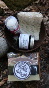 Collection of natural beauty products including a jar, bottle, and soap on a leafy background