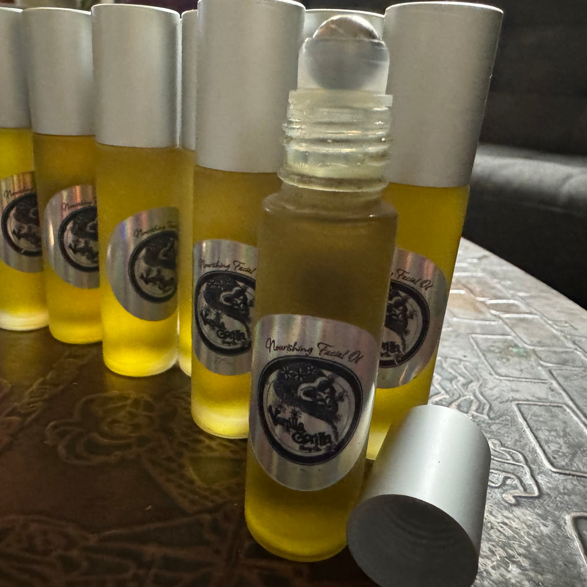 Roll-on bottles with yellow face oil liquid and silver caps on a textured surface