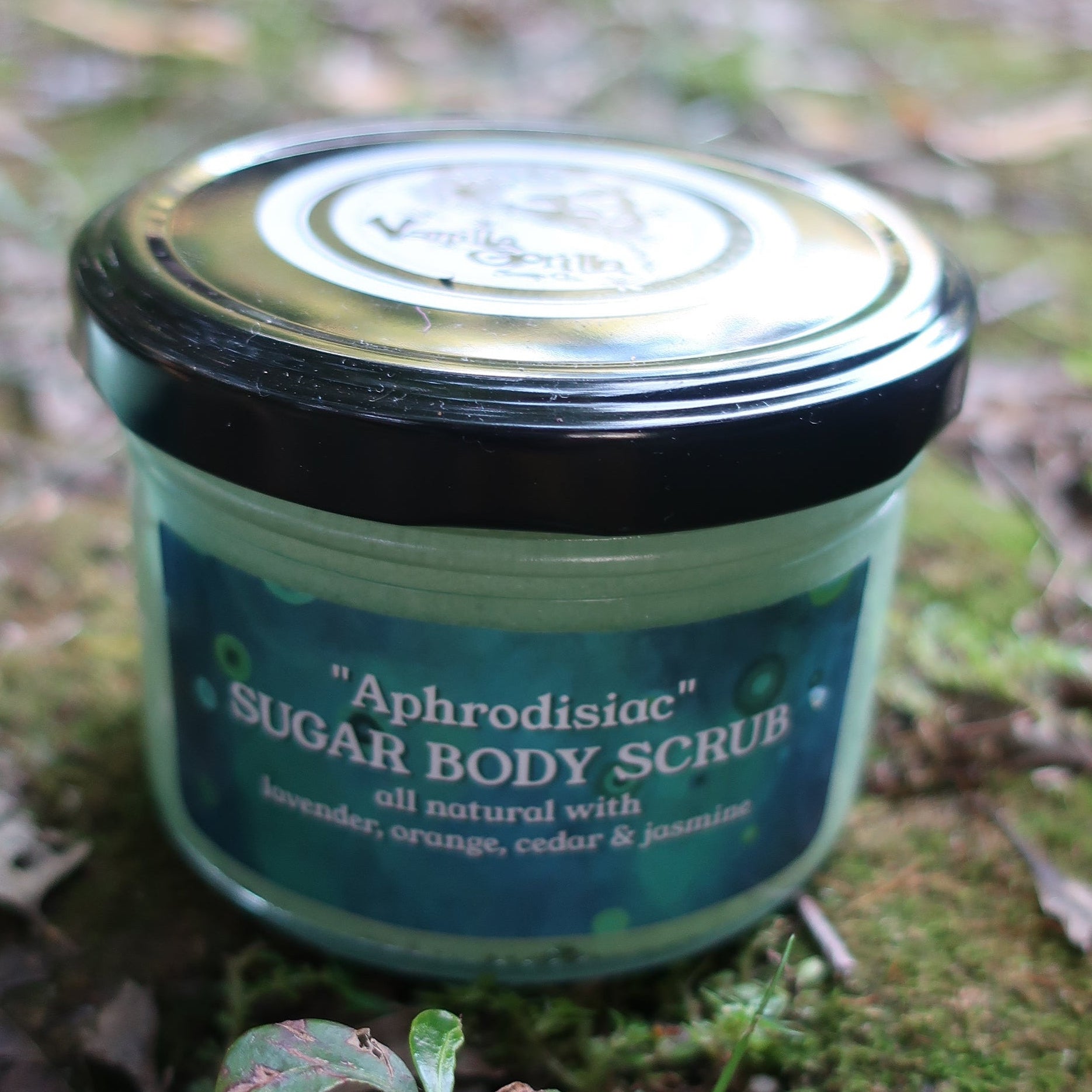 Jar of vanilla gorilla Aphrodisiac 
body scrub on a natural background with greenery