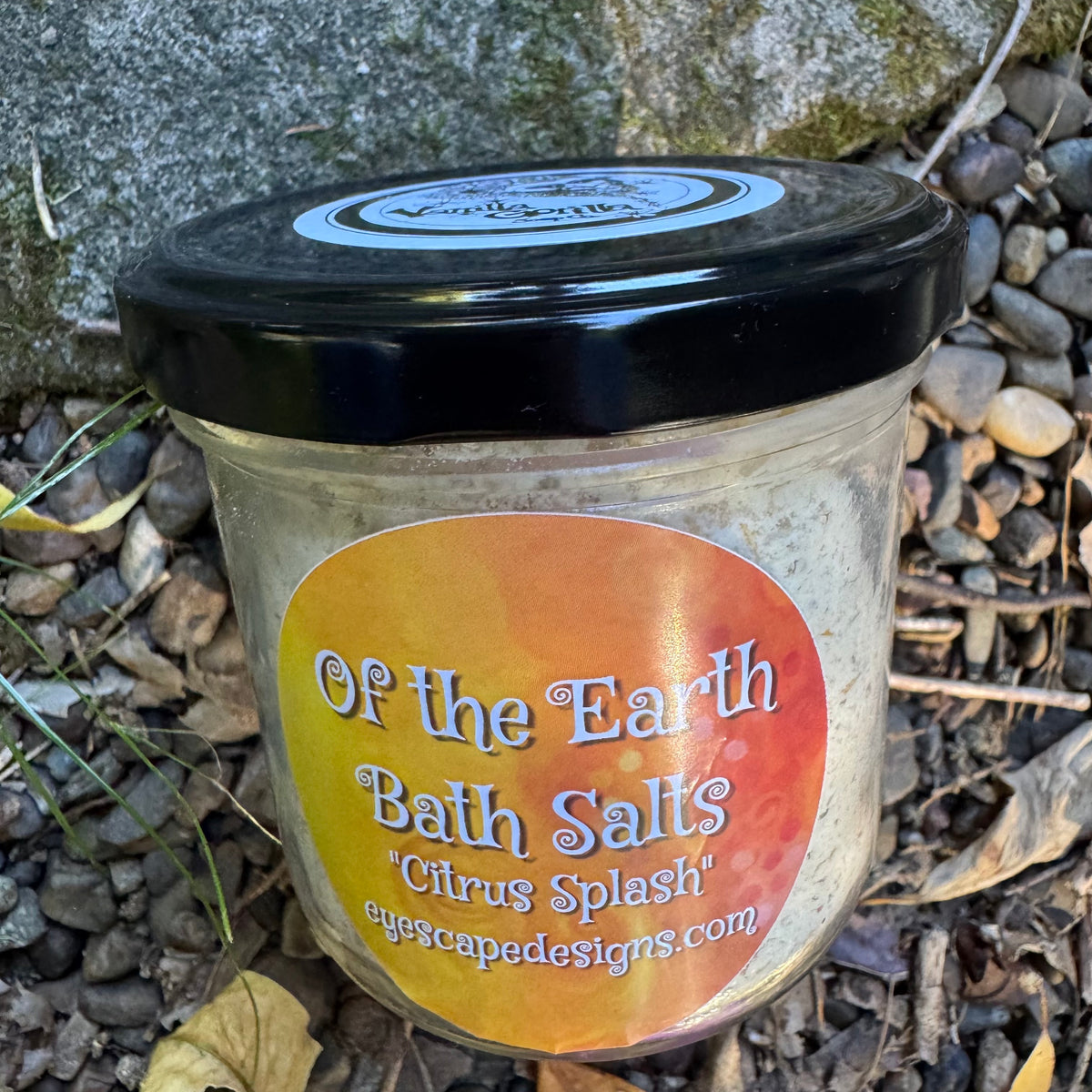 Jar of 'Of the Earth Bath Salts Citrus Splash' on a stone surface
