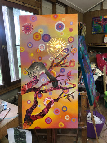 Colorful abstract painting of a brushtail possum with a stylized tree and geometric patterns on a wooden easel.