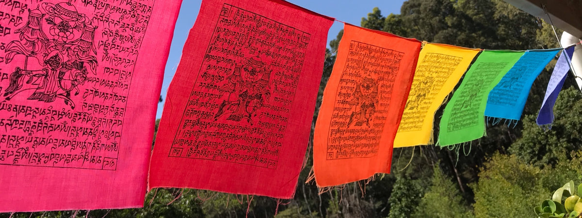 A line of rainbow prayer flags hanging on a verandah 