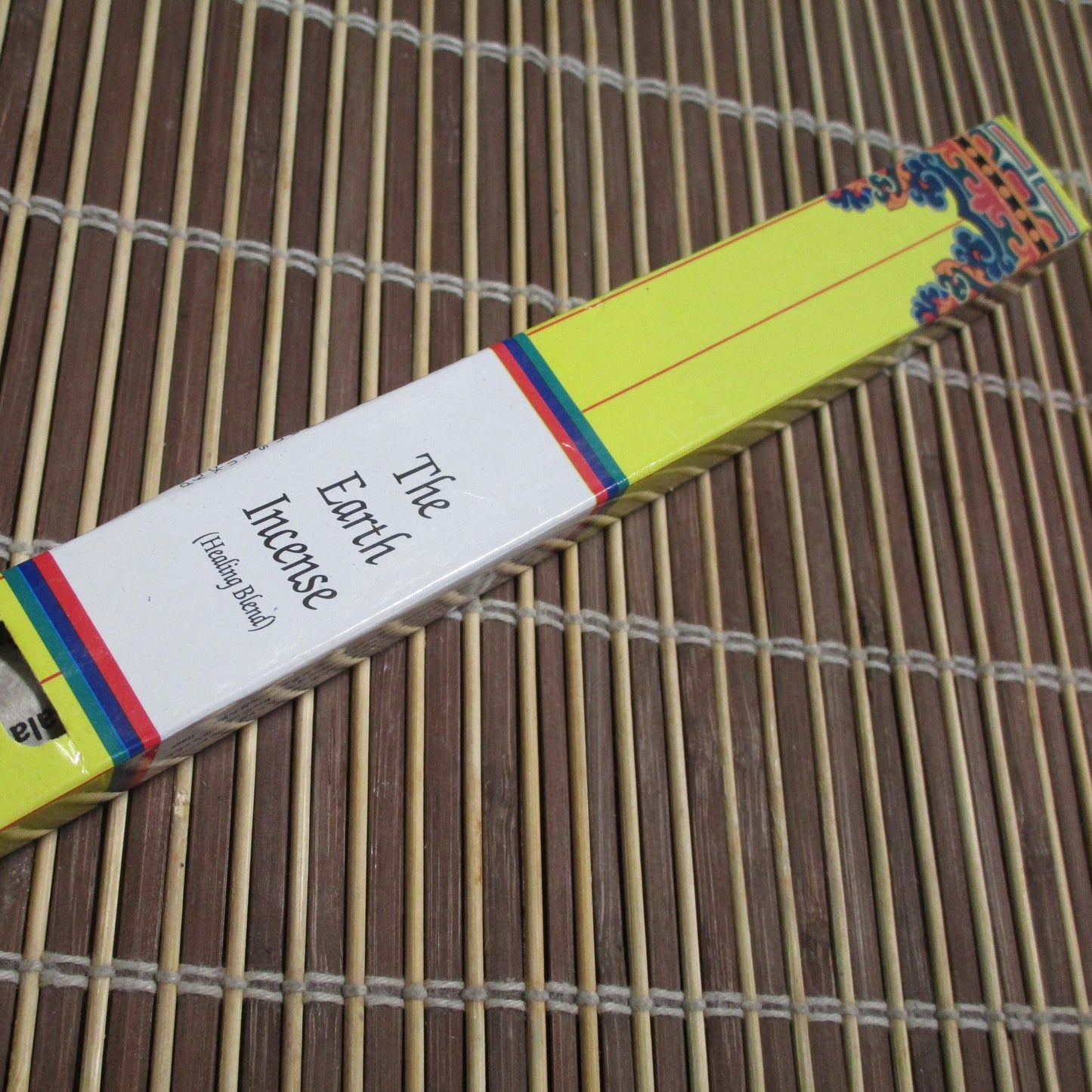 Packaging of 'The Earth Incense' showing a yellow and multicolored striped box with incense sticks visible at the top.