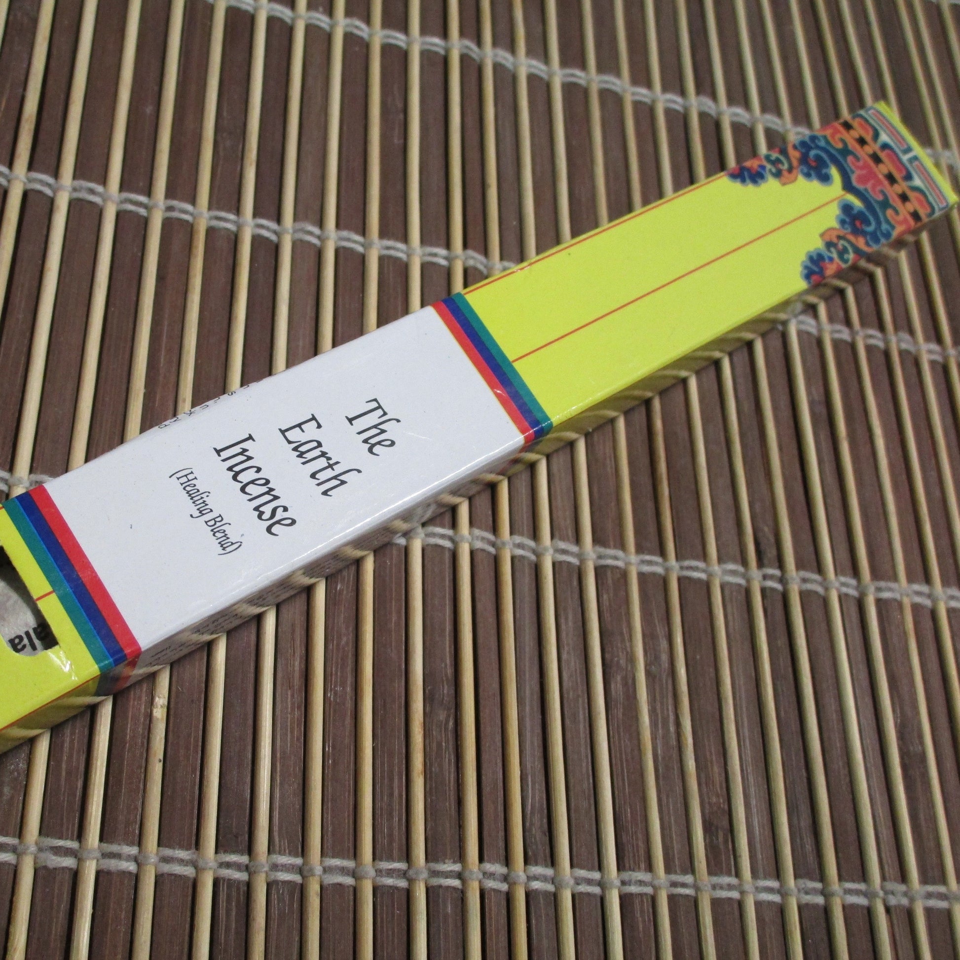Packaging of 'The Earth Incense' showing a yellow and multicolored striped box with incense sticks visible at the top.